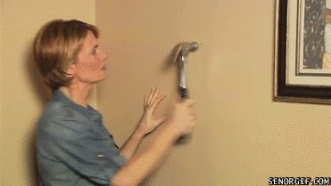 A lady hits the wall with a hammer and acts surprised when a hole appears